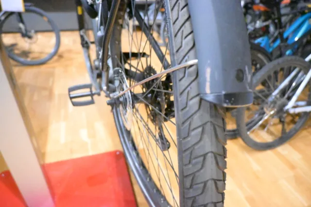 Fahrrad in der Werkstatt: Nahaufnahme von Hinterrad, Schaltung und verbogener Speiche bei der Begutachtung.