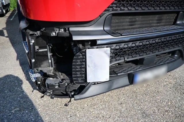 Nahaufnahme der beschädigten LKW-Front: aufgerissene Stoßstange und freigelegte Halterungen.
